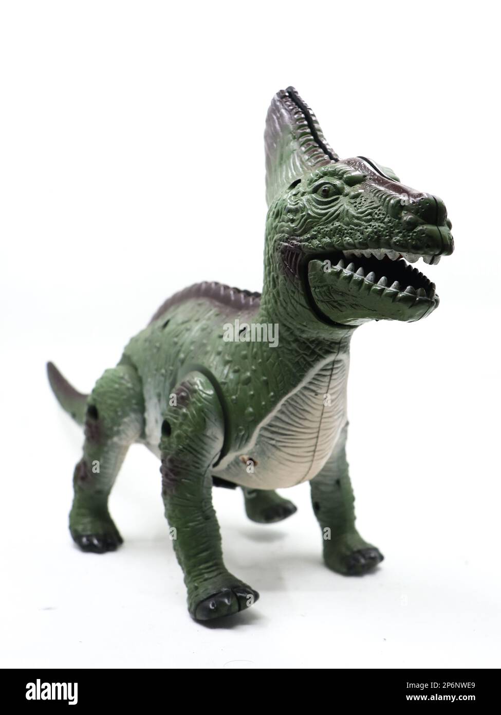 un giocattolo meccanico verde spaventoso dinosauro con denti affilati in bocca isolato su sfondo bianco Foto Stock