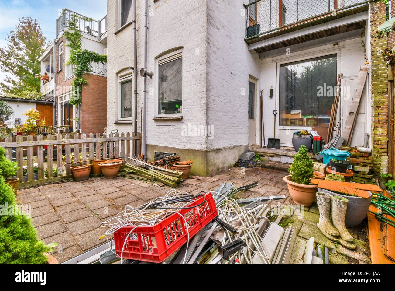 un cortile con biciclette parcheggiate a terra e piante che crescono in pentole accanto alla porta di casa Foto Stock
