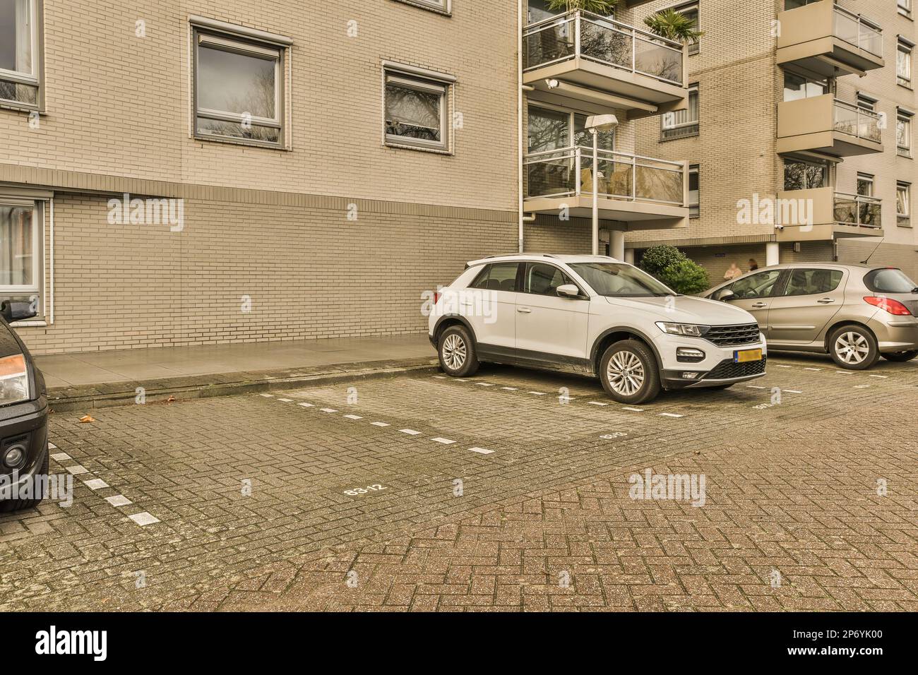 due auto parcheggiate sul lato di una strada di fronte ad un edificio di appartamenti con finestre a baldacchino Foto Stock