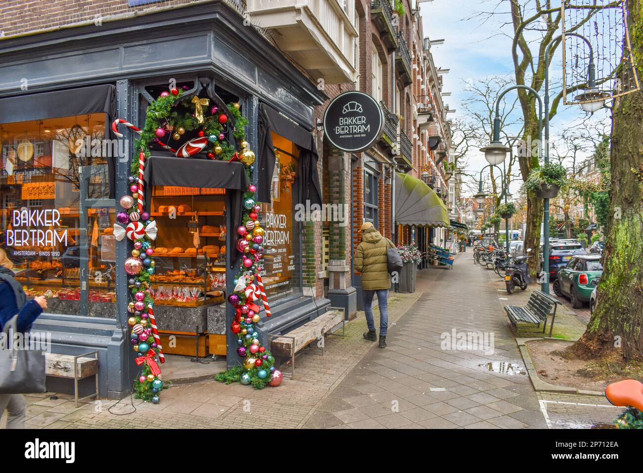 persone che camminano lungo la strada di fronte a un negozio che è decorato con ornamenti di natale e decorazioni sulle sue finestre Foto Stock