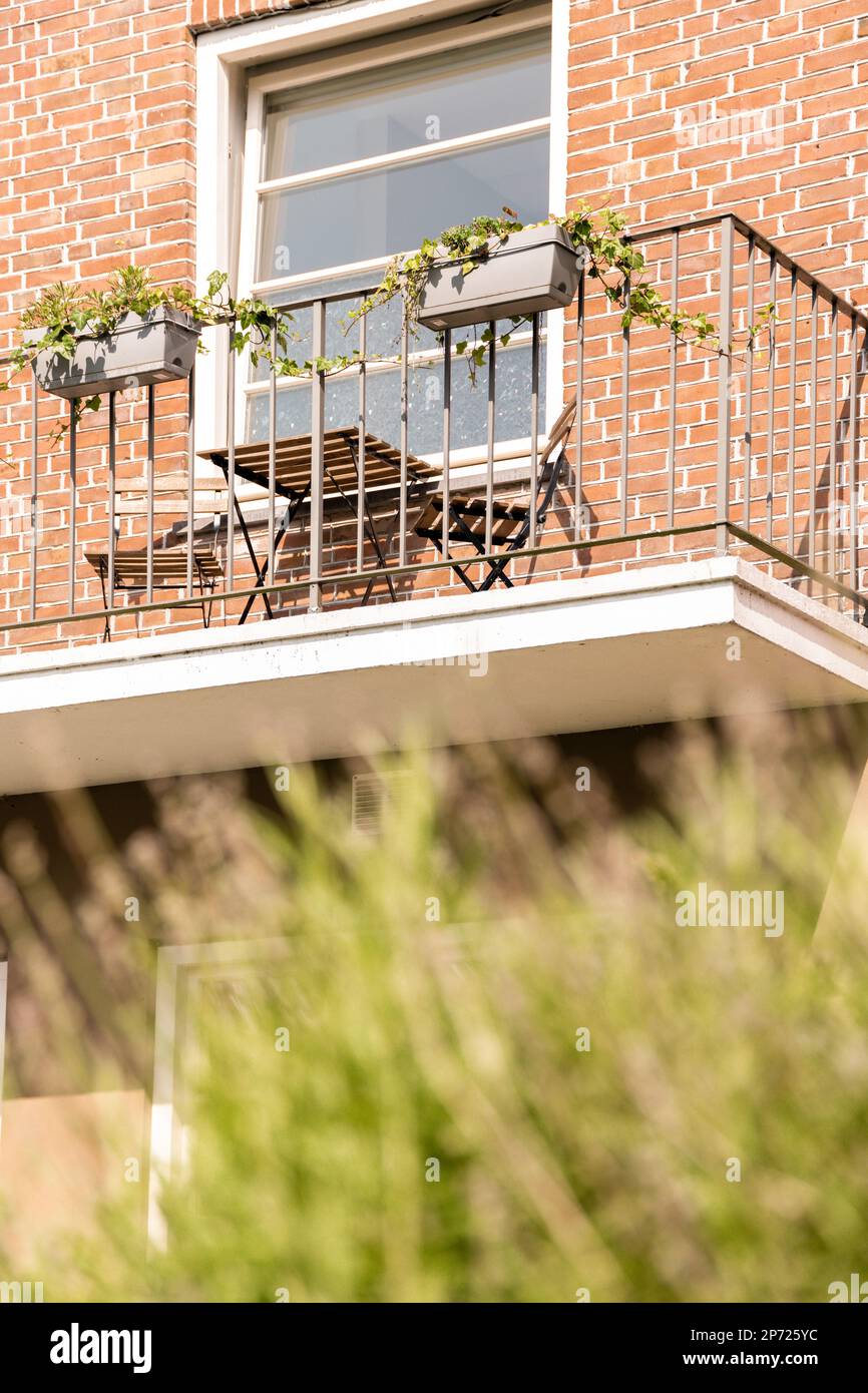 Amsterdam, Paesi Bassi - 10 aprile, 2021: Un balcone con piante che crescono sulle ringhiere balnodose e una finestra aperta nella foto è sfocata Foto Stock