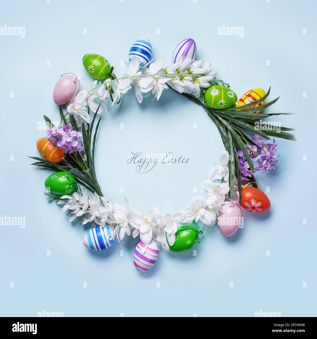 Il biglietto di Pasqua presenta una decorazione floreale circolare con uova colorate su sfondo blu pastello. Il messaggio di 'buona Pasqua' al centro di un cursi Foto Stock