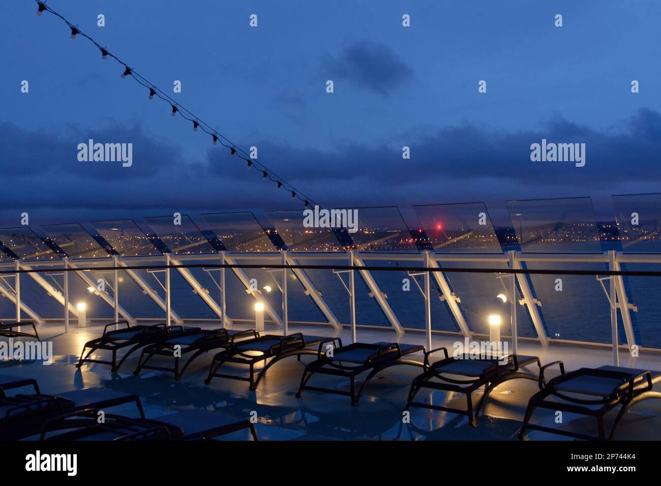 Luci di Lisbona al mattino presto, viste dal ponte anteriore di una nave da crociera attraverso pannelli di vetro con deflessione del vento. Foto Stock