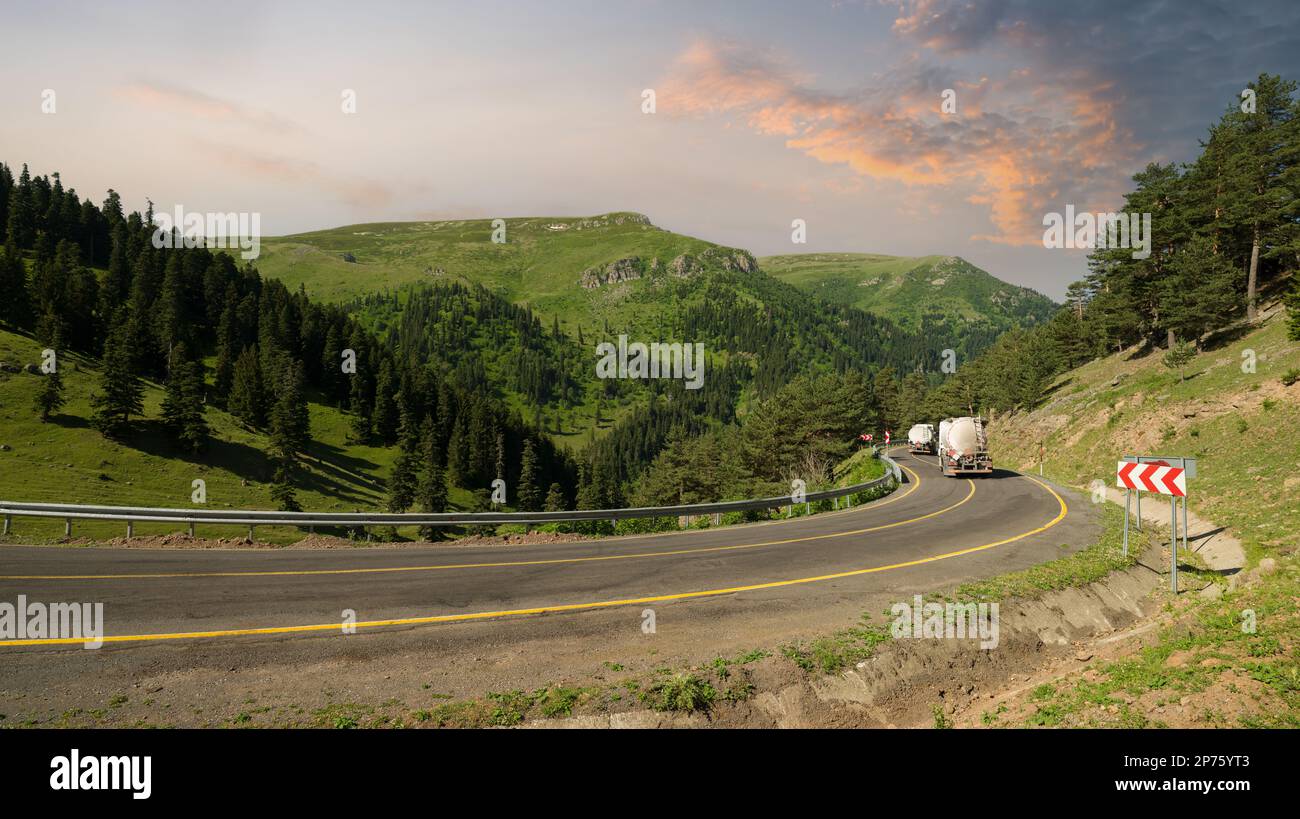 Strade di montagna curvilinee. Estate. Macchine per lavori in discesa e strade forestali asfaltate Foto Stock