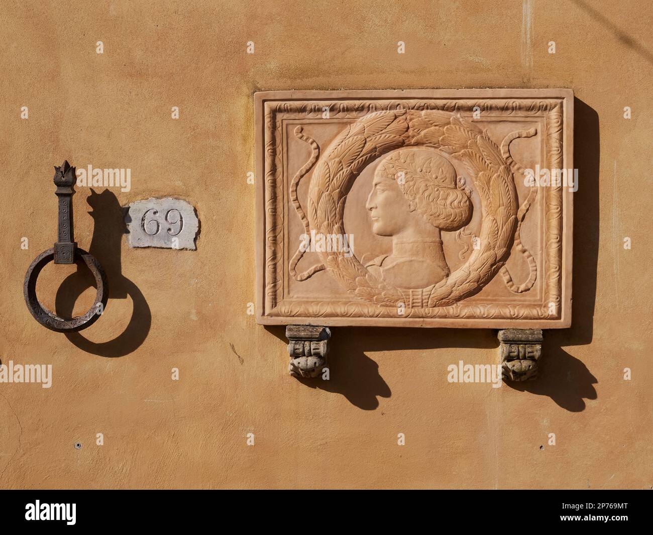 Una targa decorativa montata su un muro nel parco pubblico di Montecatini Terme con il volto di una donna in profilo nello stile di un'antica opera d'arte romana Foto Stock