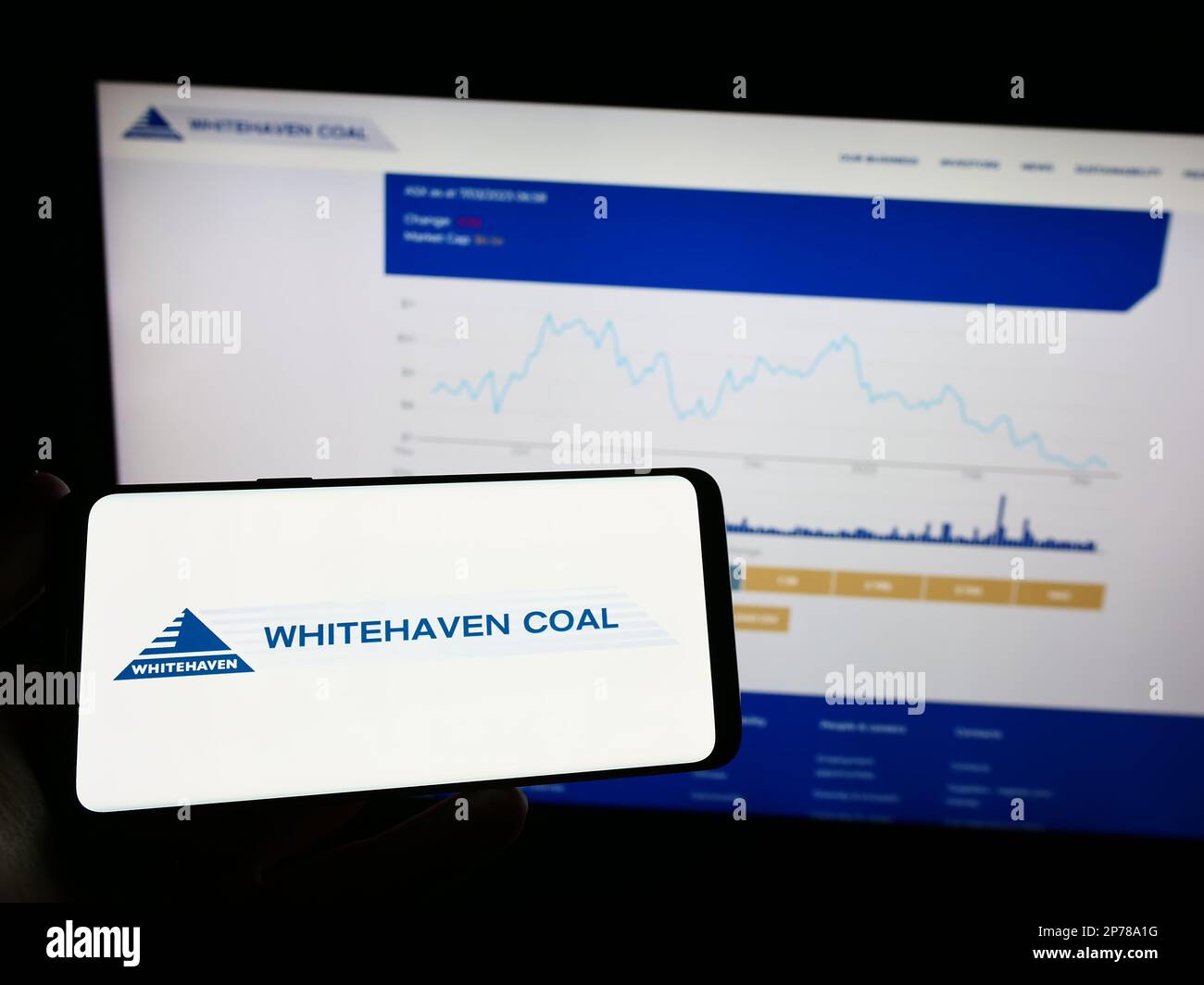 Persona che tiene un telefono cellulare con il logo della società mineraria Whitehaven Coal Limited sullo schermo di fronte alla pagina Web aziendale. Messa a fuoco sul display del telefono. Foto Stock