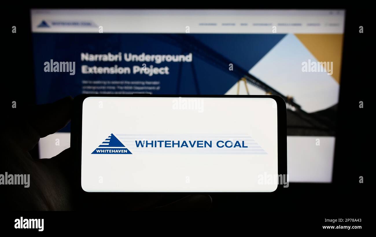 Persona che tiene in mano uno smartphone con il logo della società mineraria Whitehaven Coal Limited sullo schermo davanti al sito Web. Messa a fuoco sul display del telefono. Foto Stock