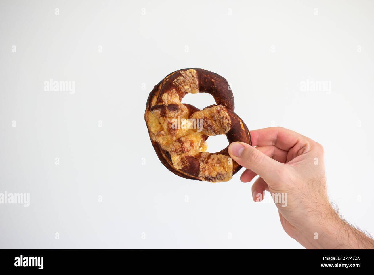 Pretzel appena appoggiato a casa tenuto in mano da mano maschio caucasica. Primo piano ripresa in studio, isolata su bianco. Foto Stock