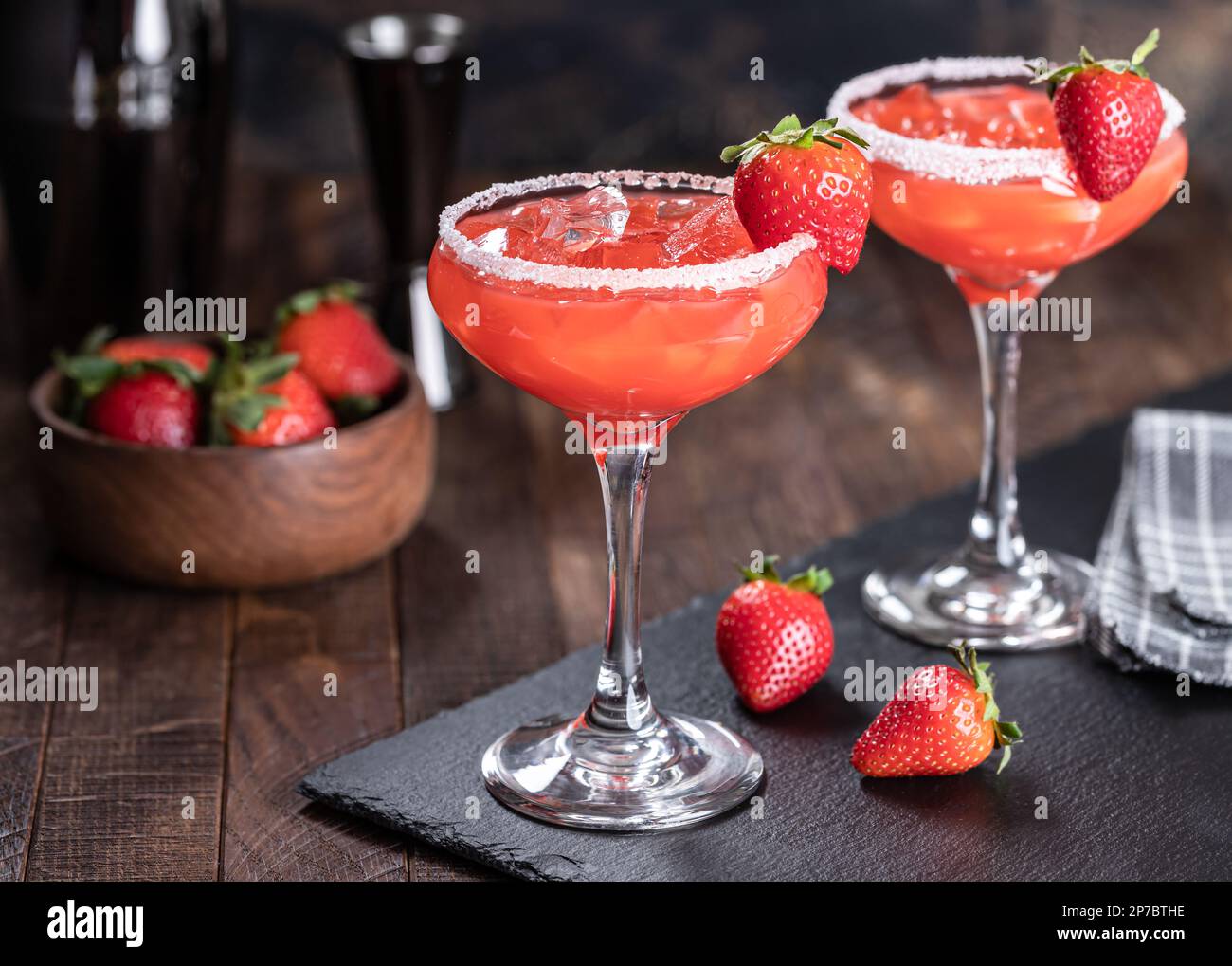 Cocktail margarita di fragole guarnito con fragole e bordo salato su una tavola di ardesia nera Foto Stock