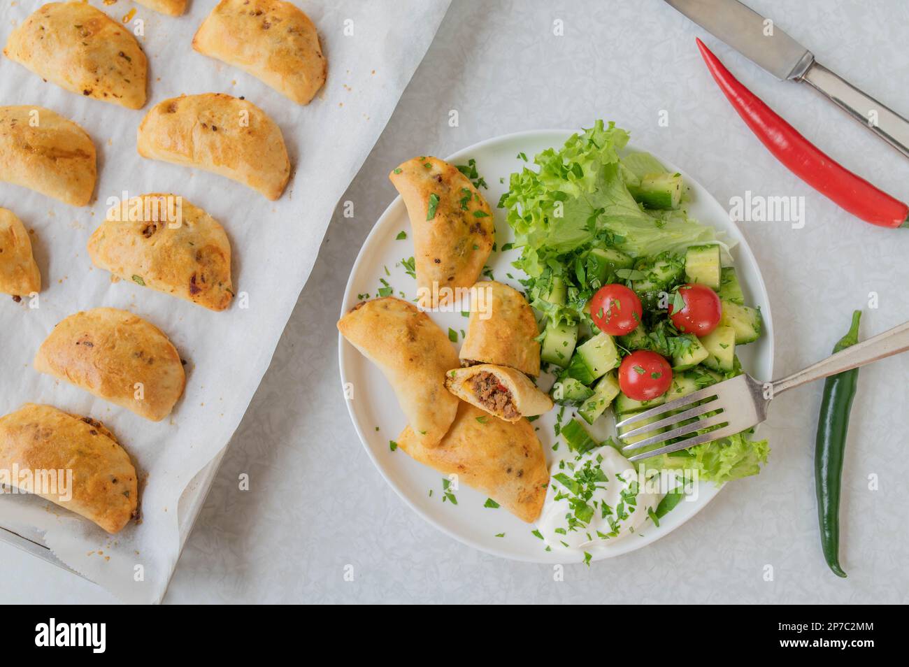 Empanadas con macinato di manzo piccante, ripieno di formaggio con insalata su un piatto. giacitura piatta Foto Stock