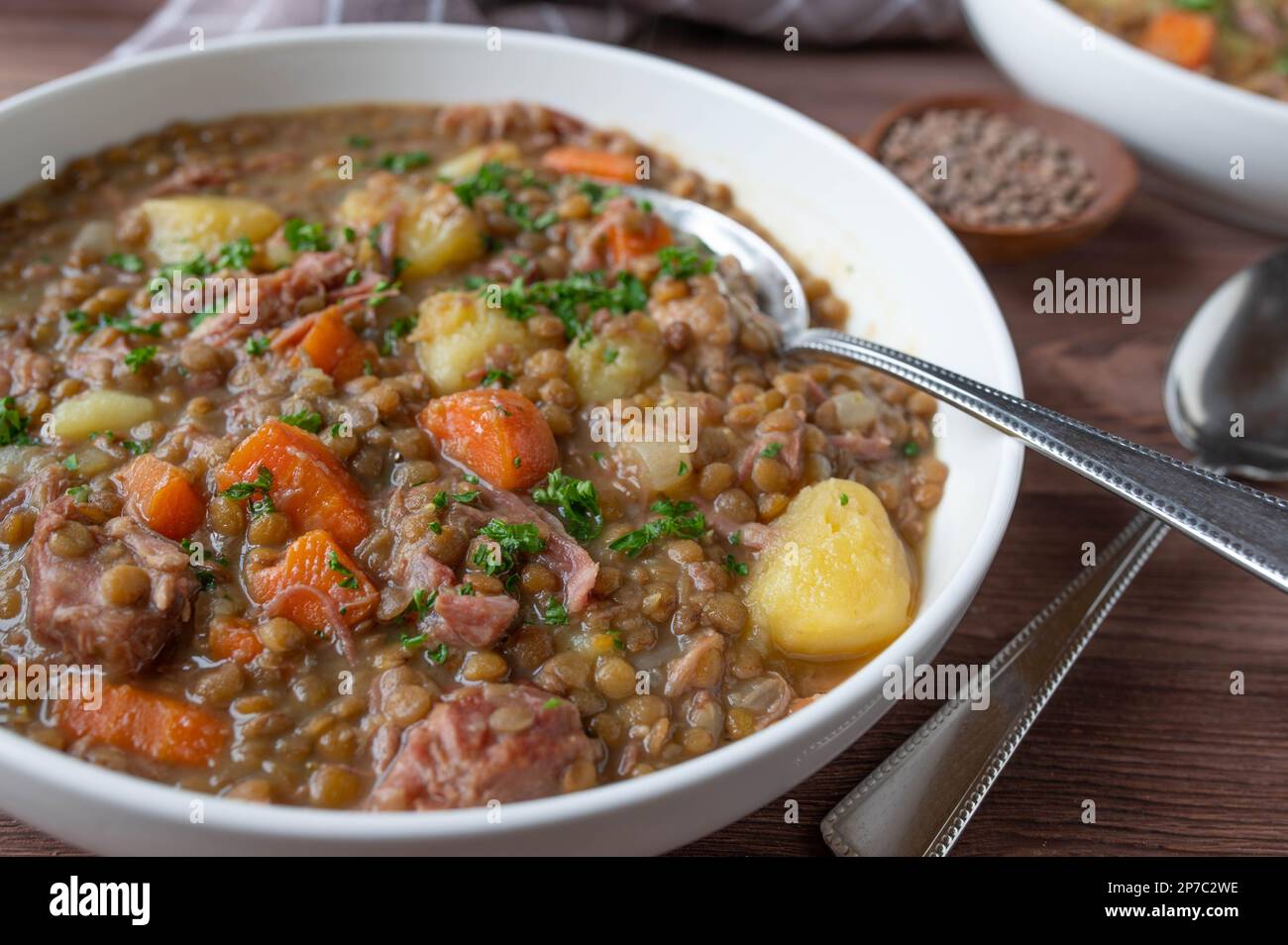 Stufato di lenticchie o zuppa con lenticchie, verdure, patate e carne di maiale in un piatto con cucchiaio Foto Stock