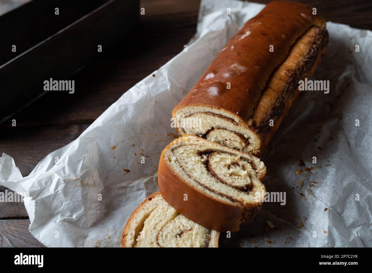 Torta di pane o torta di lievito con cannella, burro, ripieno di zucchero. Servito intero con fette su tavolo di legno Foto Stock
