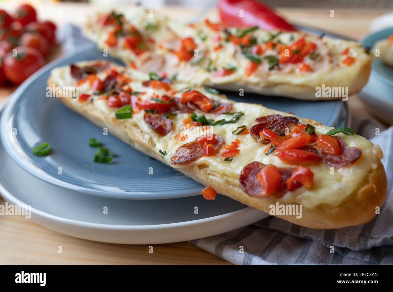 Baguette di salame con formaggio, peperoni e erba cipollina su un piatto Foto Stock