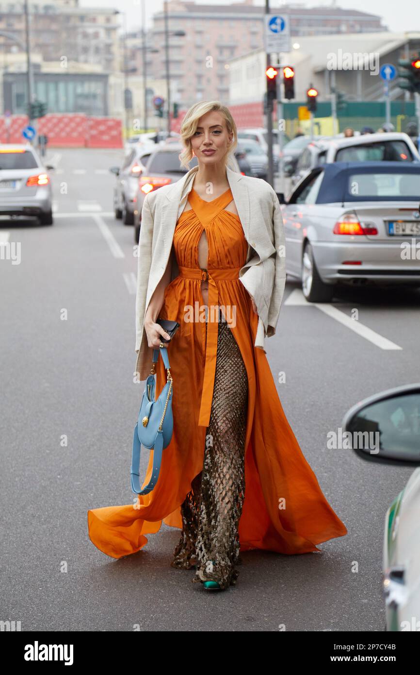 MILANO, ITALIA - 22 FEBBRAIO 2023: Donna con abito arancione e giacca beige  prima della sfilata Alberta Ferretti, Milano Fashion Week Street Style Foto  stock - Alamy