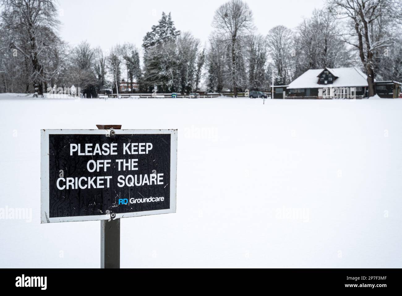 Campo da cricket coperto di neve con cartello Reading si prega di tenere lontano da Cricket Square, Farnham, Surrey, Inghilterra, Regno Unito Foto Stock