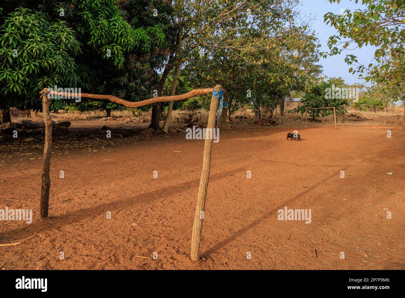 pali di legno e una meravigliosa traversa fanno l'obiettivo su un campo da calcio sabbioso vuoto in un villaggio rurale africano due piccole capre segnano il cerchio centrale Foto Stock