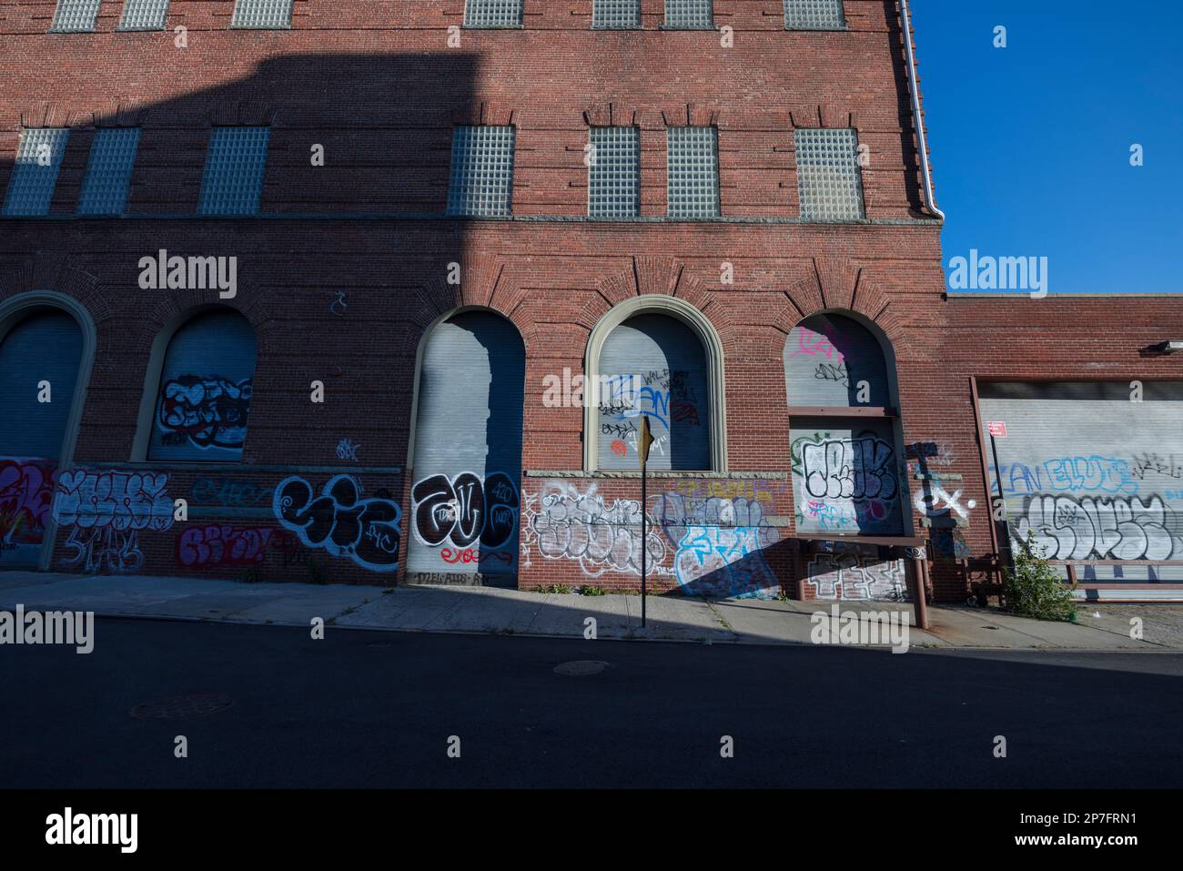 Graffiti dipinti sulla facciata dell'edificio chiuso della fabbrica a Brooklyn, New York City. Foto Stock