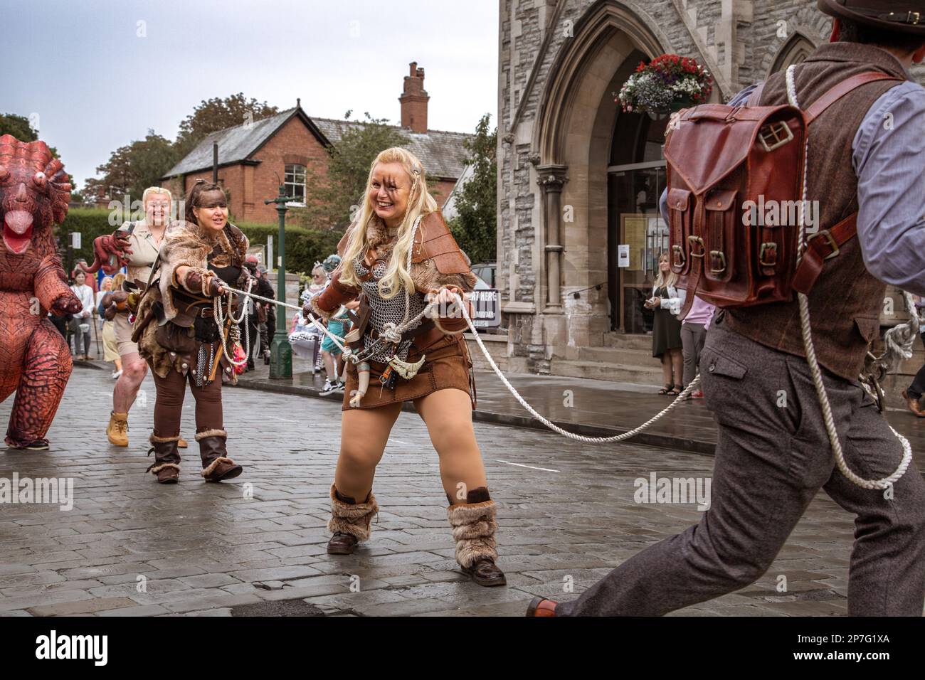 Un gruppo di avventurieri steampunk, collegati da corda si tirano lungo la strada in un evento steampunk. Foto Stock