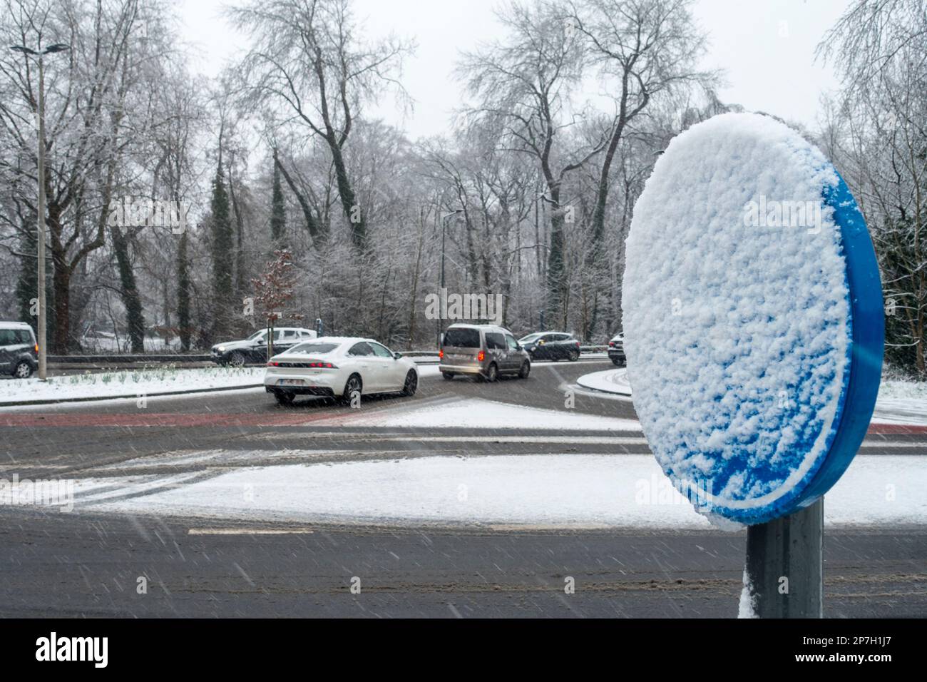 Auto su un vivace incrocio scivoloso e segnaletica stradale coperta di neve durante l'inaspettata tarda notte di slittino e la doccia di neve nel marzo 2023, Gent, Belgio Foto Stock