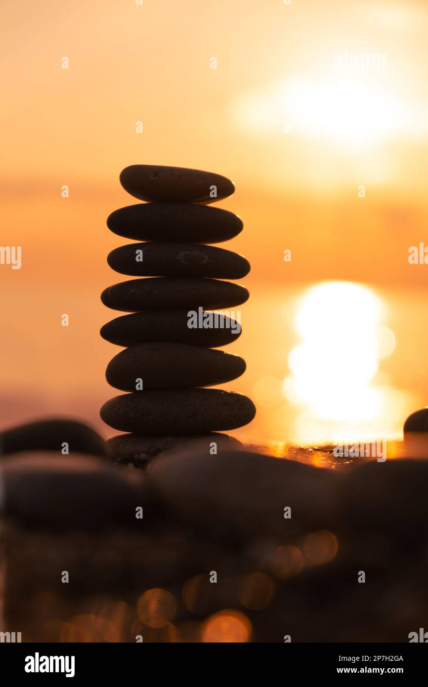 İmage verticale, profilo equilibrato piramidale di ciottoli sulla spiaggia al tramonto. Pietre Zen sulla spiaggia di mare, meditazione, spa, armonia, calma. Foto Stock