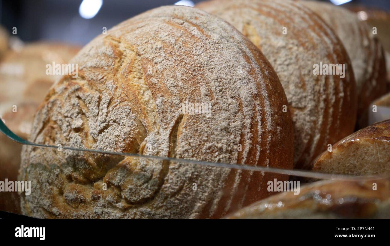 Pagnotte di pane di segale si trovano sulla mensola di legno del forno. Primo piano. Shopping al negozio di alimentari. Concetto di vendita di cibo Foto Stock