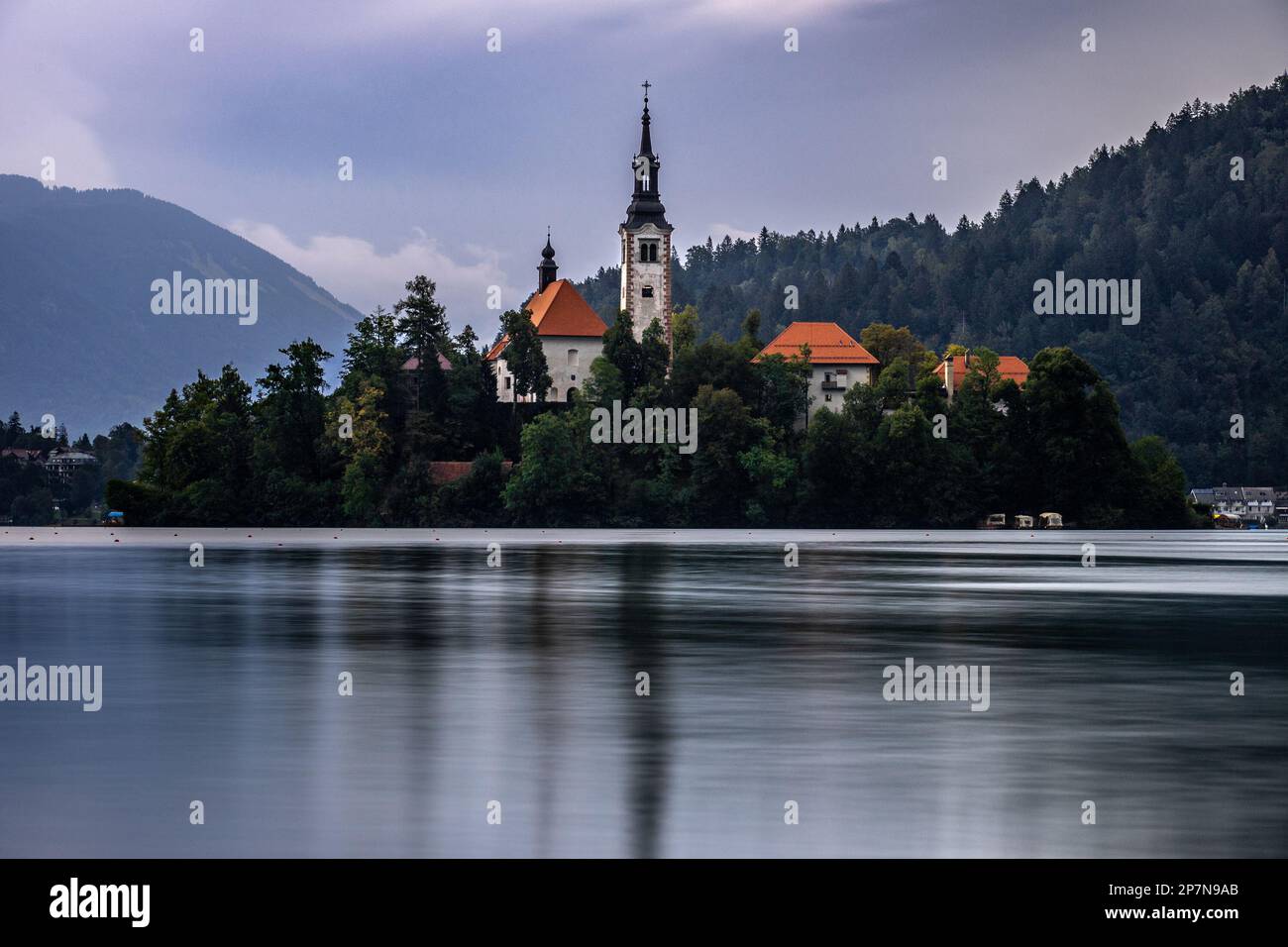 Foto simmetrica a lunga esposizione dell'Isola del Lago di Bled con l'Assunzione della chiesa di Maria riflessa nell'acqua Foto Stock