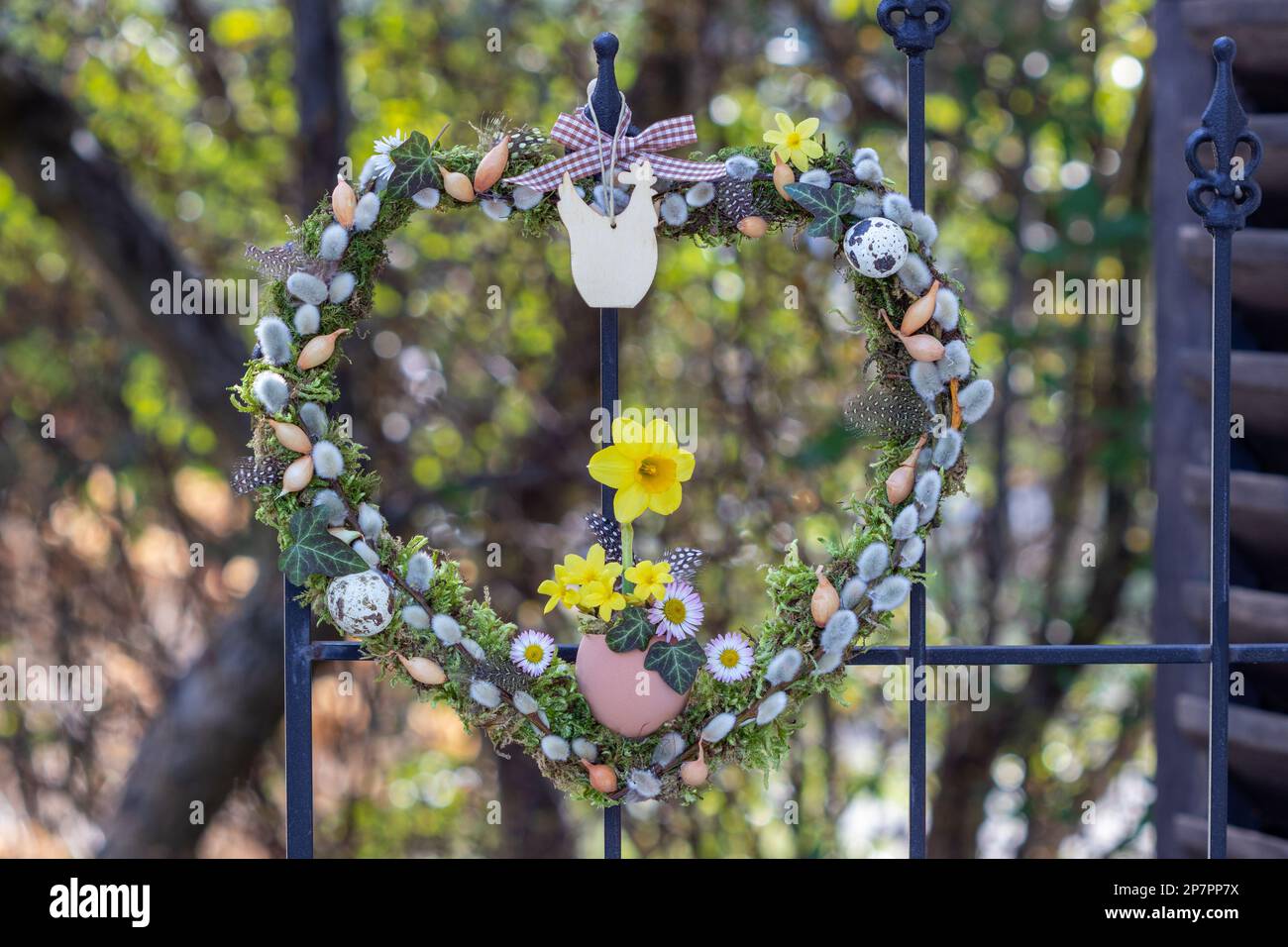 corona a forma di cuore con moos, cetriolini di salice, set di cipolle e fiori di narciso Foto Stock