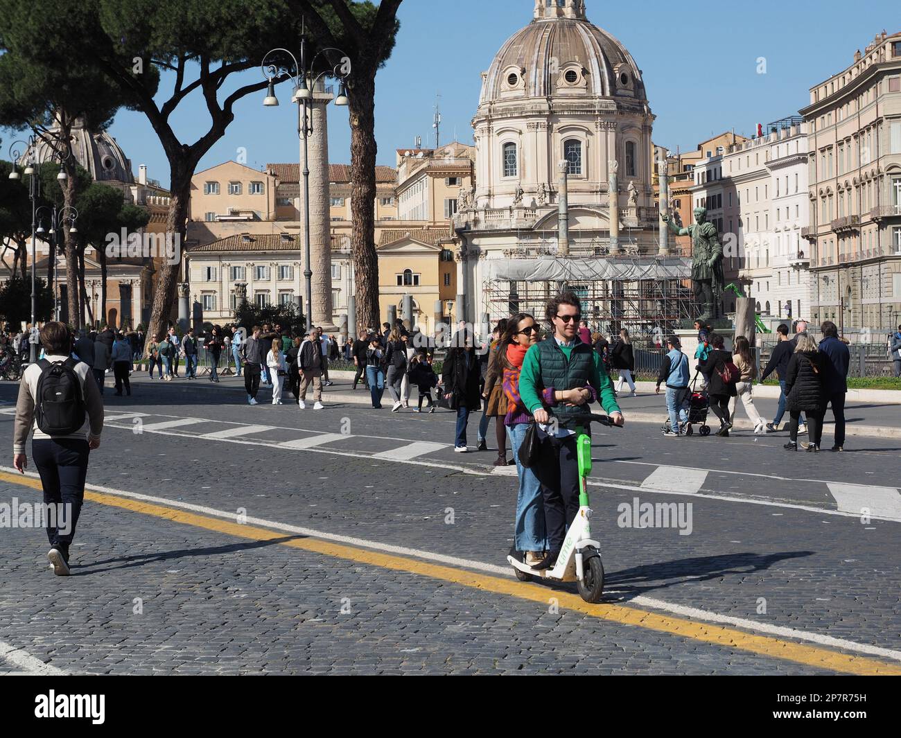 Giovane coppia che utilizza uno scooter elettrico a noleggio in Via dei fori Imperiali a Roma Foto Stock