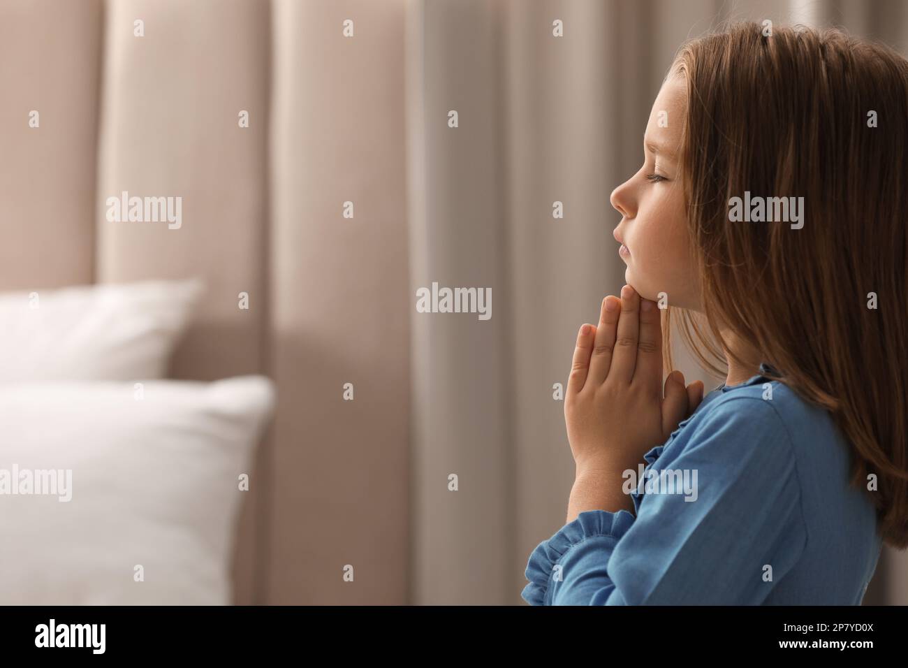 Ragazza cute che dice la preghiera di bedtime a casa. Spazio per il testo Foto Stock