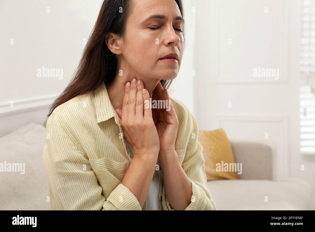 Donna matura che fa l'esame di auto della tiroide nel paese Foto Stock