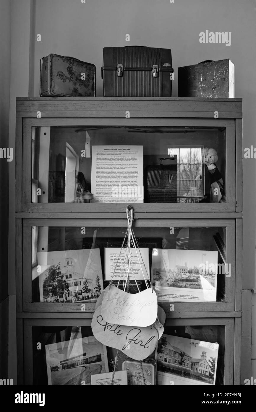 Un armadietto di curiosità con porte di vetro che espongono scatole da pranzo vintage, bambole e fotografie nell'edificio principale del Museo Tuck di storia di Hampton Foto Stock