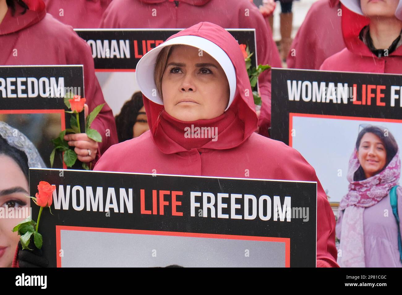 Londra, Regno Unito. 8th marzo, 2023. Donne anglo-iraniane vestite di mantello ispirate ai personaggi di Magaret Atwood's, 'The Haindmaid's tale'. La marcia che si è svolta per sostenere le donne in Iran ha proseguito silenziosamente lungo Whitehall, mentre i partecipanti portavano un ritratto di qualcuno che è stato ucciso o imprigionato dal regime islamico dal settembre dello scorso anno. Credit: Undicesima ora di Fotografia/Alamy Live News Foto Stock