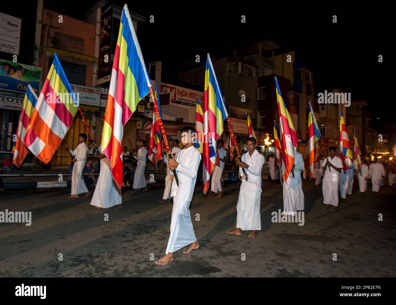 I portatori di bandiera buddisti sfilano lungo una strada a Kandy in Sri Lanka durante l'Esala Perahera (grande processione). Foto Stock
