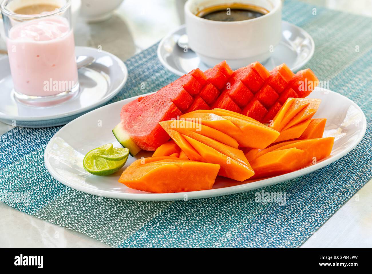 Bella frutta a fette in piatto bianco sul tavolo da pranzo al mattino, stile artistico tailandese per la decorazione di frutta, frutta tailandese sana, cocomero, papaia. Foto Stock