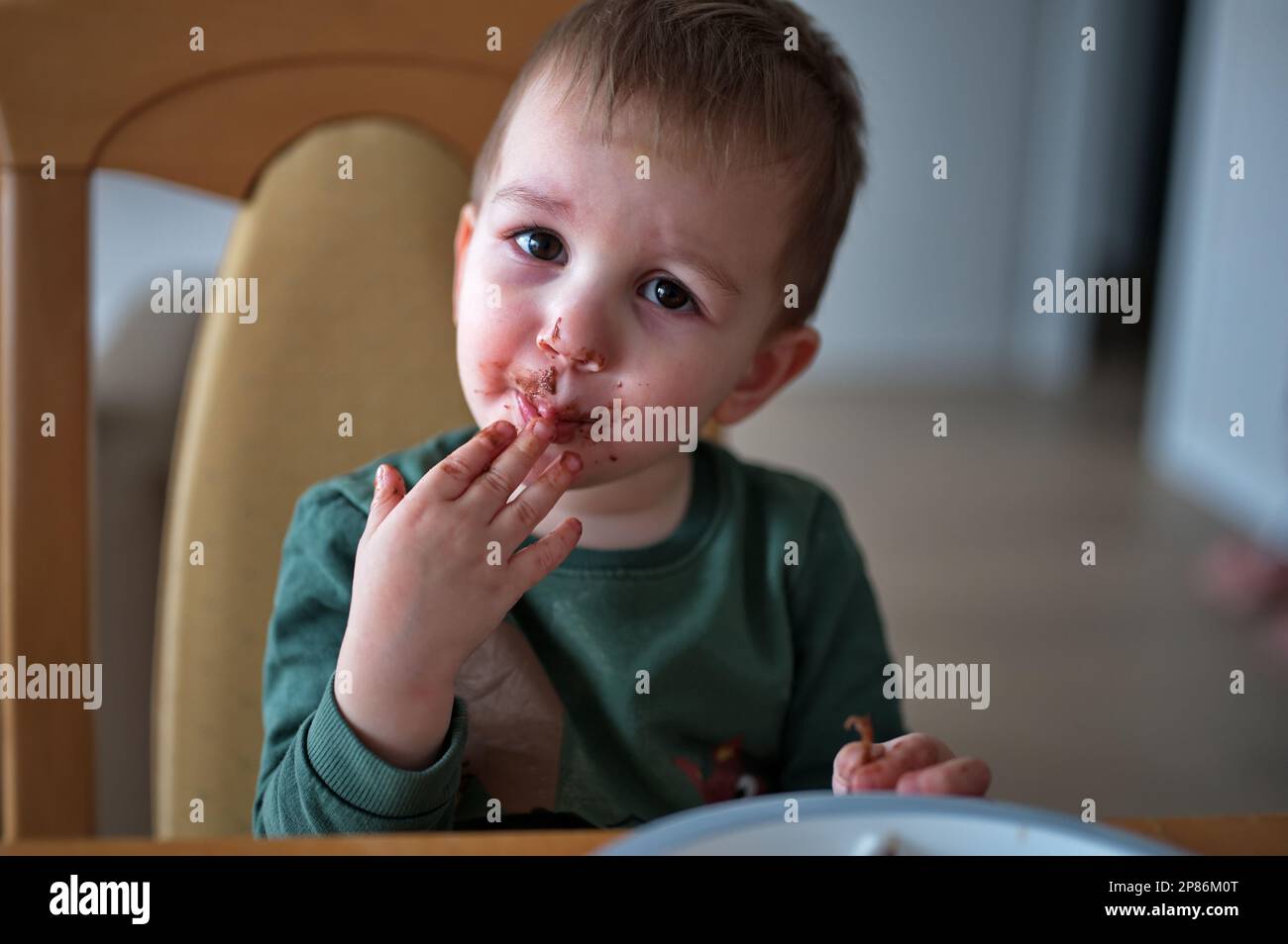 Il bambino piccolo e carino si spalmò di cioccolato intorno alla bocca Foto Stock