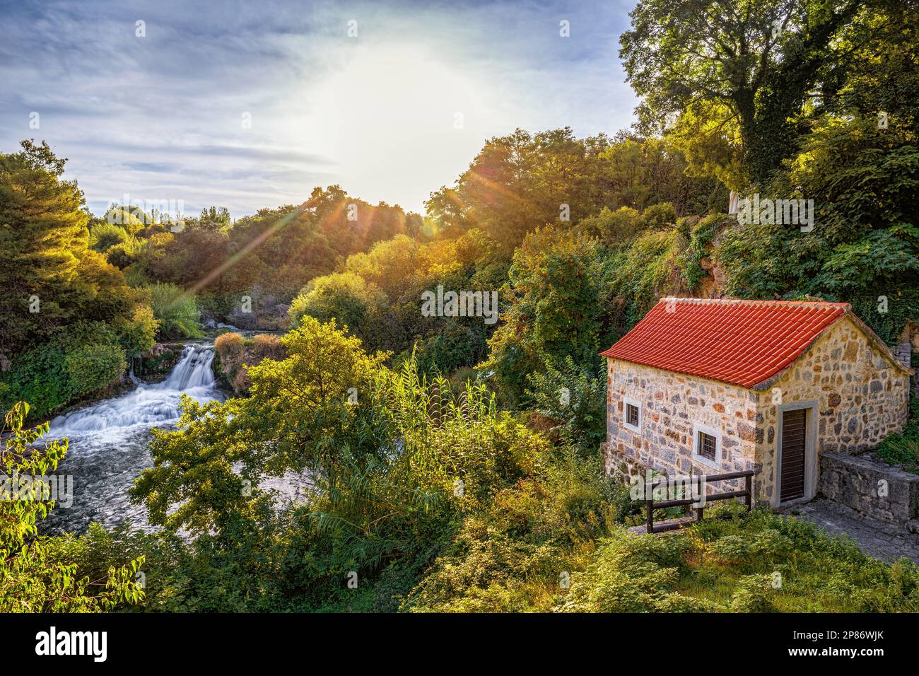 Krka, Croazia - bellissimo scenario di alba estiva di una piccola casa di pietra alle cascate Krka nel Parco Nazionale Krka, Dalmazia con il caldo mattino colorato fol Foto Stock