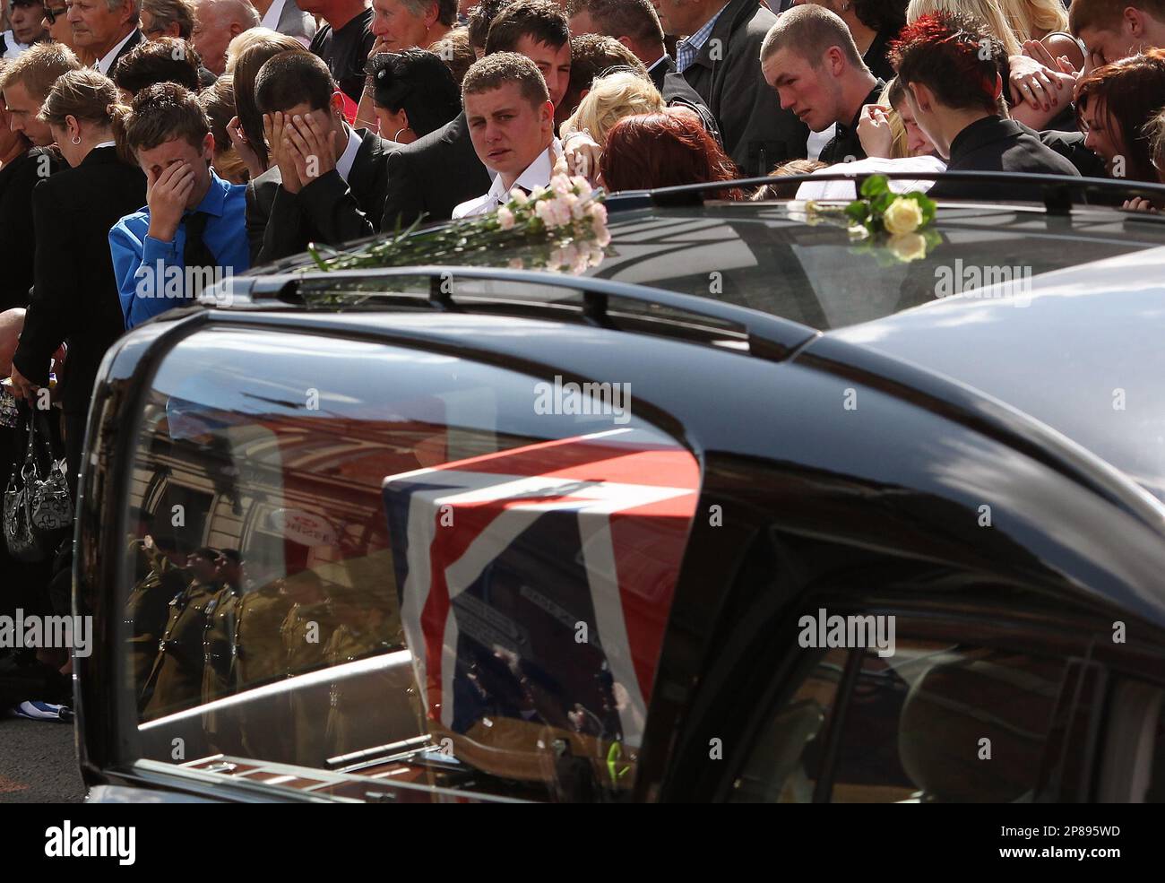 Friends of fallen serviceman Jimmy Backhouse react as the cortege of hearses carrying the bodies of eight British soldiers killed during the bloodiest 24-hours for British forces since the invasion of Afghanistan in 2001 pass mourners lining the street on Tuesday July 14, 2009 in Wootton Bassett, England. (AP Photo/Simon Dawson) Foto Stock