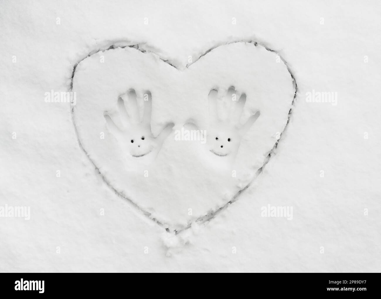 Vista dall'alto del grande cuore trainato dalla neve e due impronte con sorriso al centro. Concetto romantico e divertente. Spazio di copia. Foto Stock