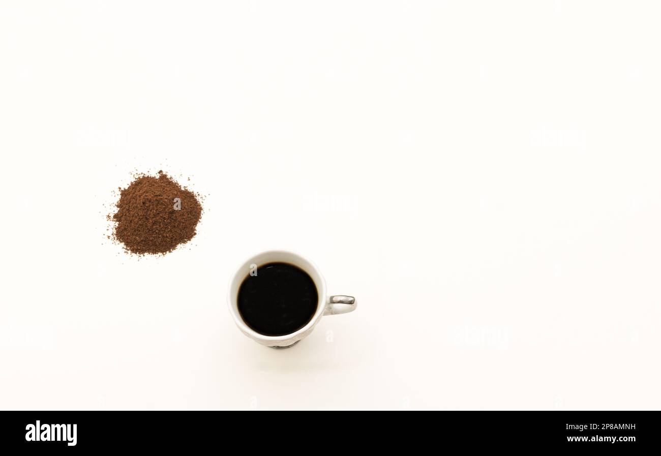 caffè macinato con una tazza di caffè su sfondo bianco Foto Stock