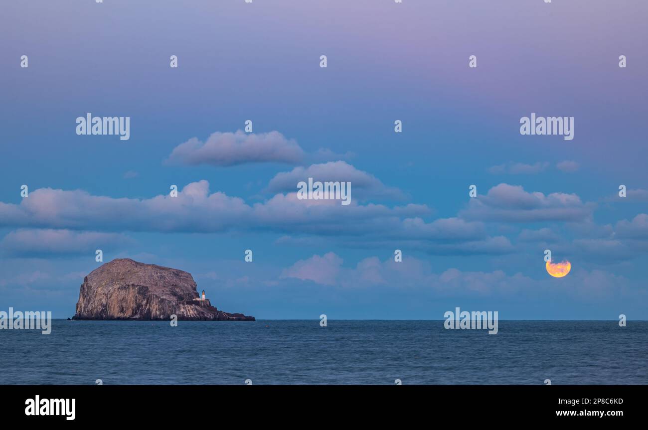 Isola di Bass Rock al crepuscolo con luna piena che si innalza dietro le nuvole. Firth of Forth, Scozia, Regno Unito Foto Stock