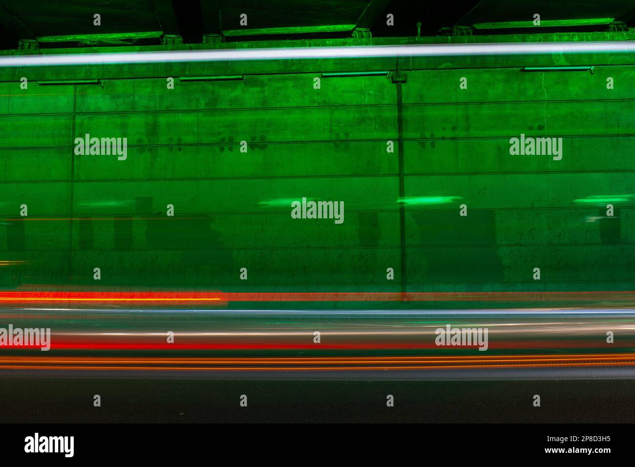 Luci per auto sentieri di fronte a una parete illuminata da luce verde con spazio per il testo. Adatta come immagine di sfondo. Foto Stock