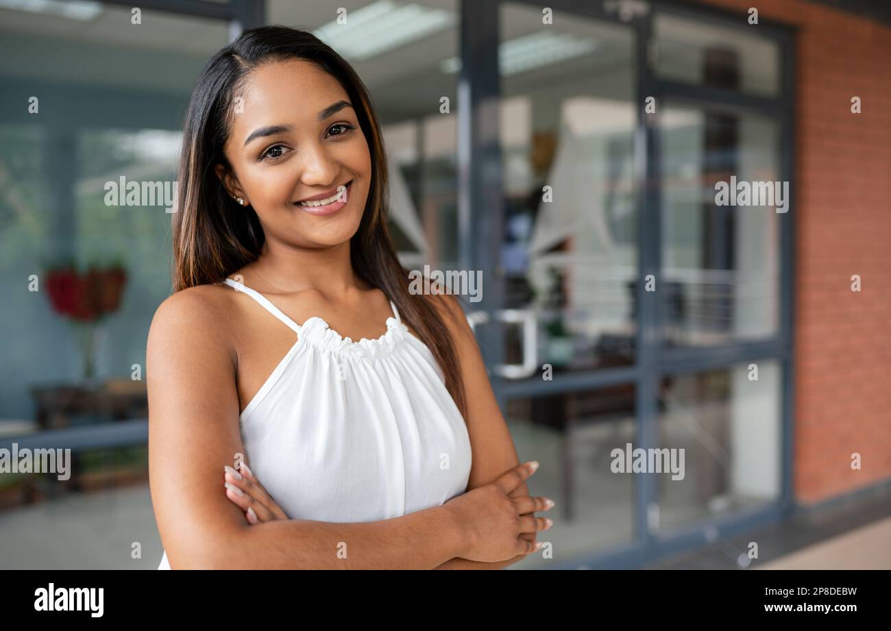 Una giovane, allegra donna indiana si alza con un sorriso luminoso sul viso guardando direttamente nella macchina fotografica, irradiando emozioni e felicità. Foto Stock