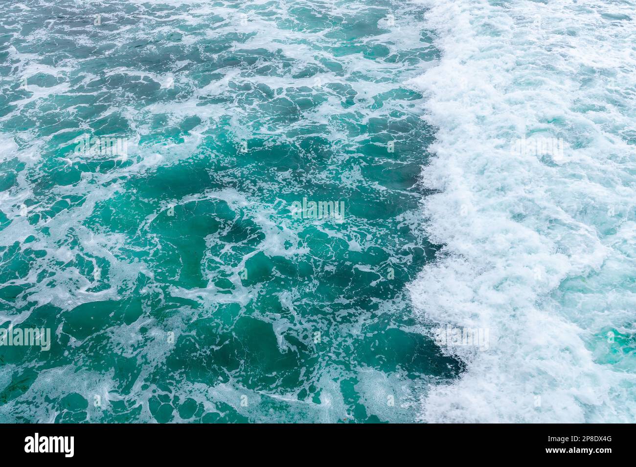 Vista dall'alto di un'onda che si schiantava. Spruzzi d'acqua blu, sfondo oceano. Foto Stock