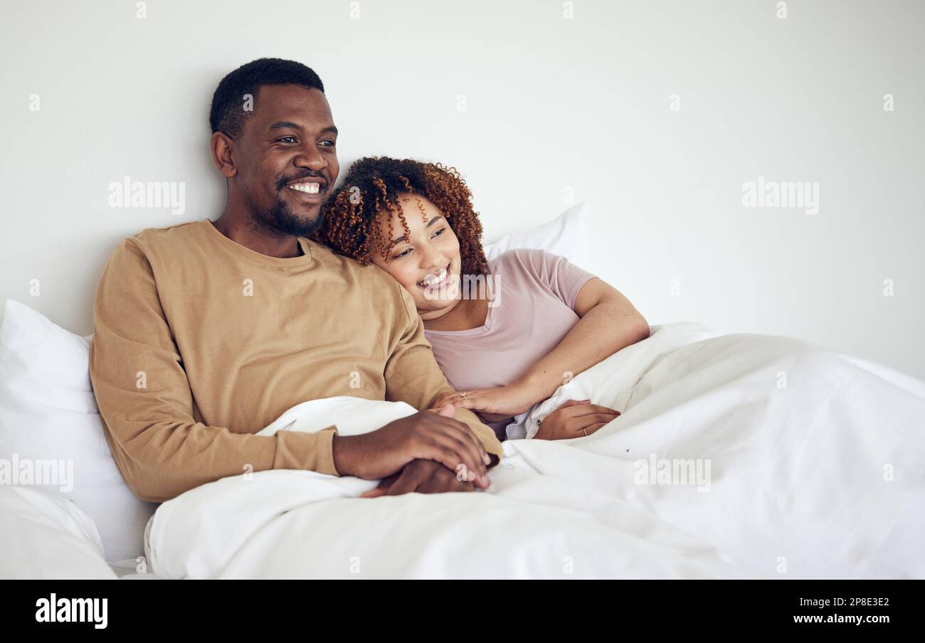 Coppia nera, TV in camera da letto guardando e riposo a letto al mattino insieme con amore e cura. Felicità, casa e sorriso di una donna e di un uomo che si sentono felici Foto Stock