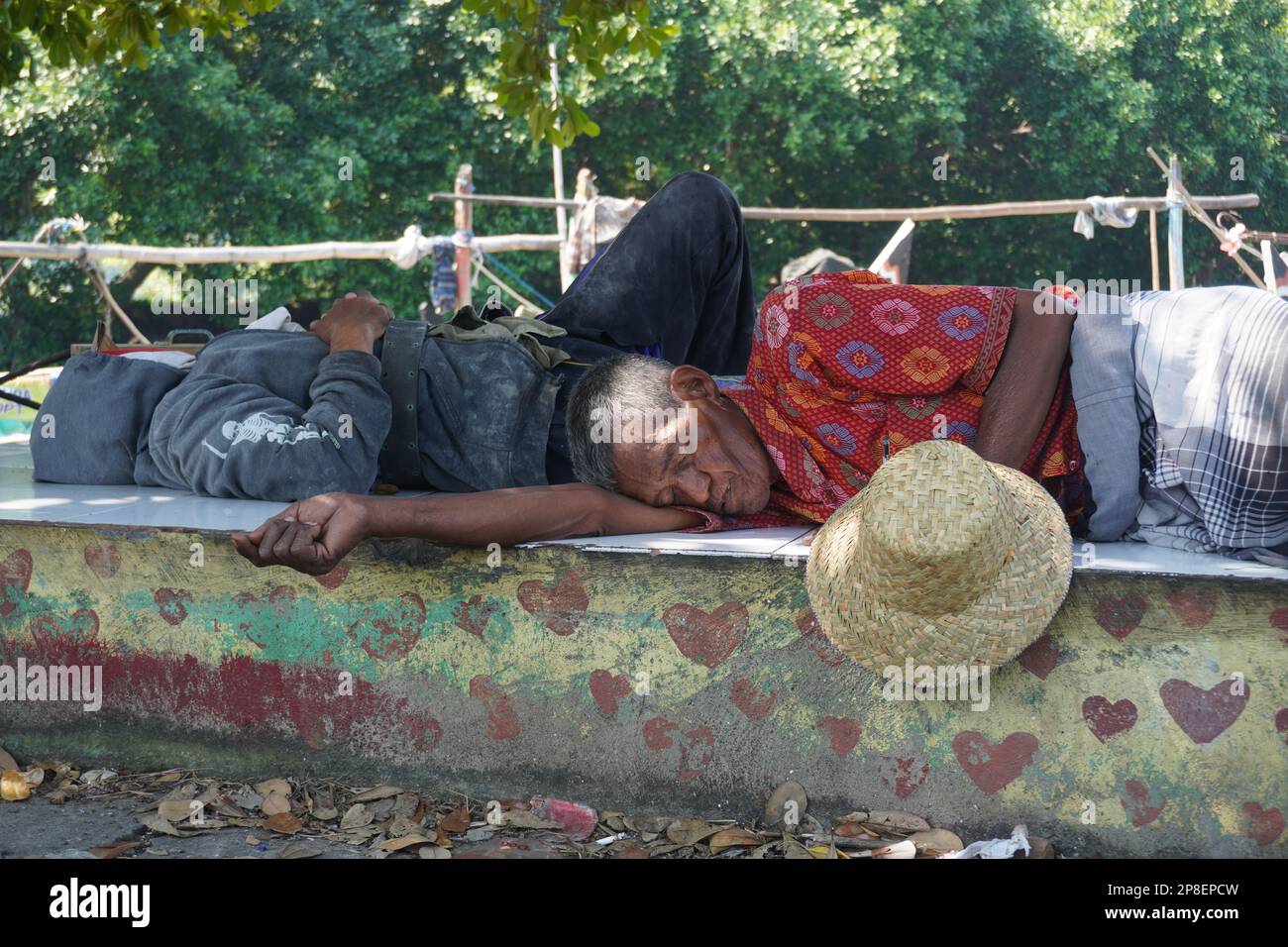 vecchio pescatore in un cappello che dorme vicino alla loro barca Foto Stock