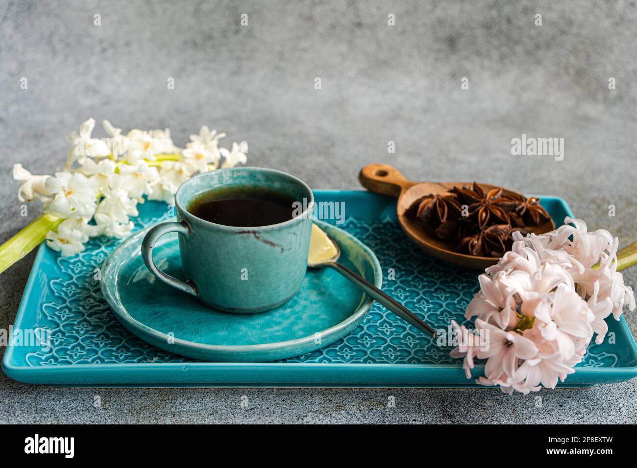 Tazza di caffè nero con una ciotola di anice stellato e fiori di giacinto rosa e bianco Foto Stock