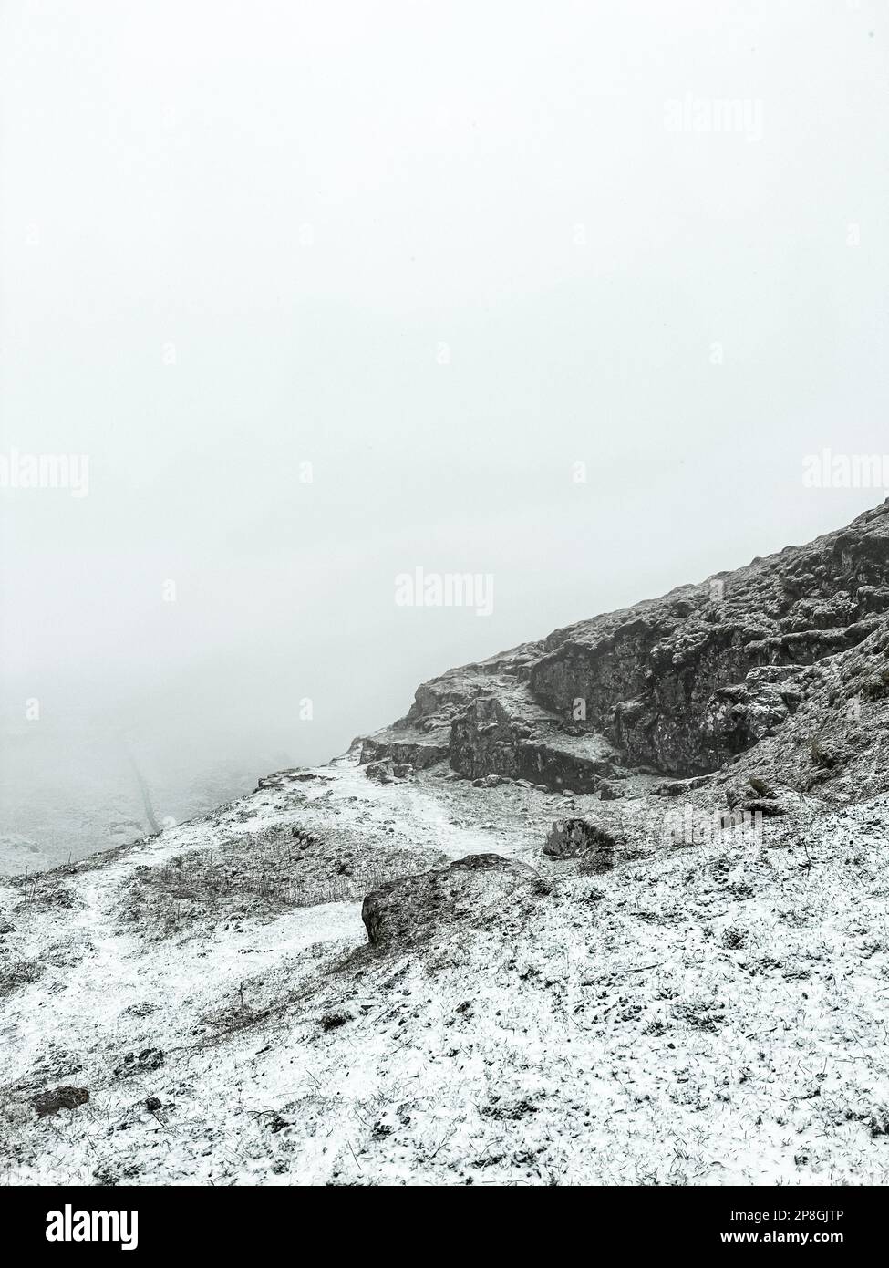 Montagne rocciose innevate sul Winnat's Pass in una giornata nuvolosa nel Peak District, Inghilterra Foto Stock