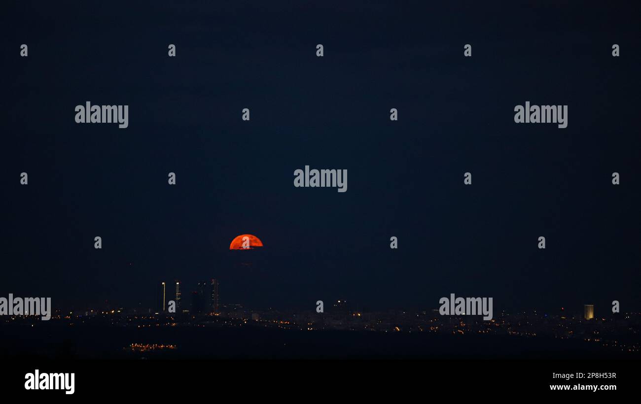 Cielo nero con sole rosso tra gli edifici della città di madrid Foto Stock