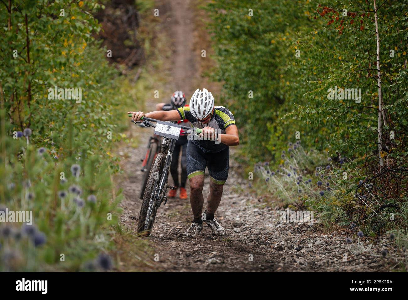 due ciclisti salgono con la loro mountain bike. salita pesante su pendenze fangose. gara ciclistica di fondo Foto Stock
