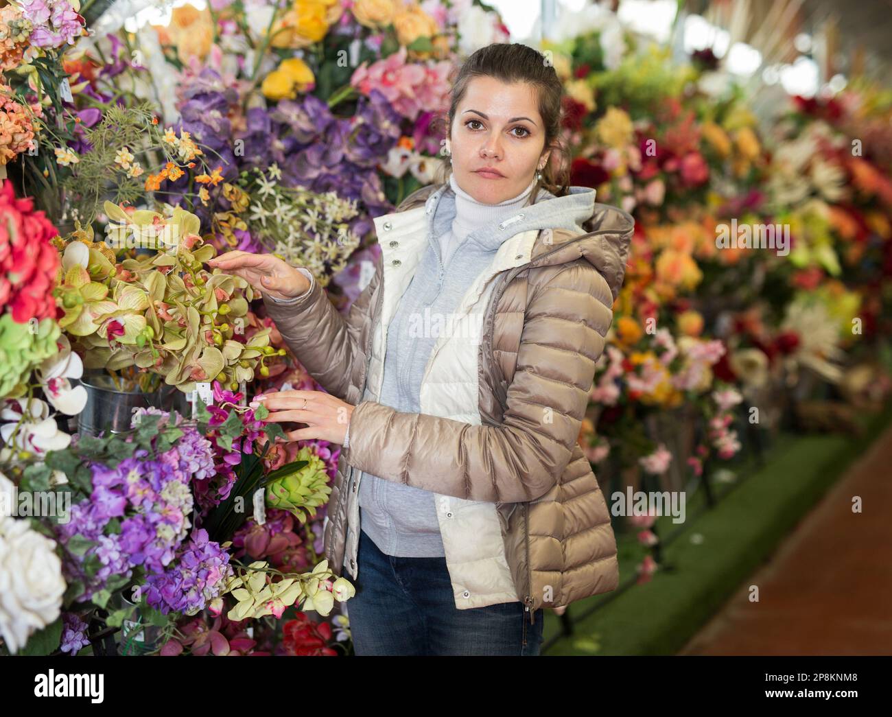 Donna scelta fiori in negozio Foto Stock